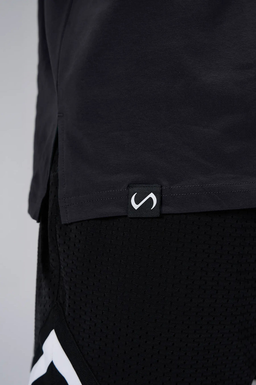 Black Sinister Cotton Luxe Oversized Tee showing side split hem, woven hem clip label, and Cotton Luxe DNA fabric by TLF Apparel – detail view