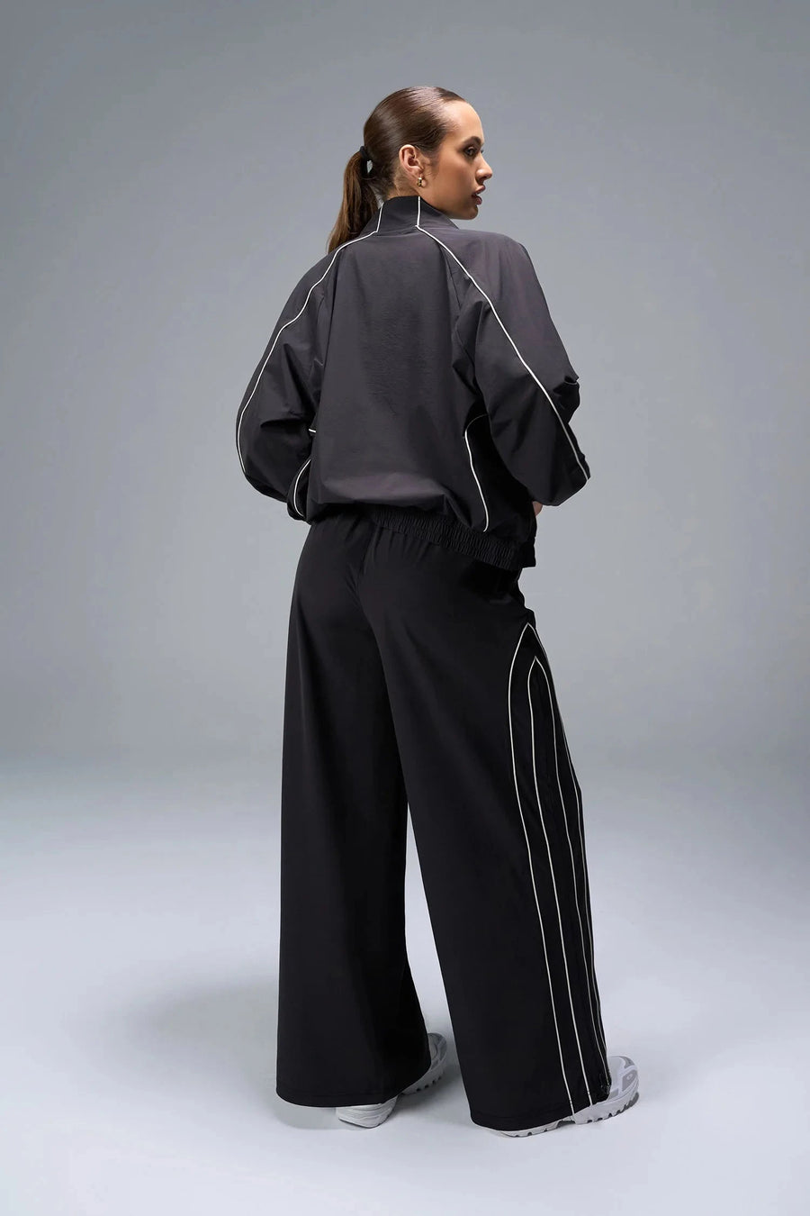 Back View of Black TLF Baggy Track Pants (Women’s GTS Gym-To-Street Edition) featuring side pockets and reflective piping details.
