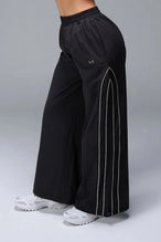 Side View of Black TLF Baggy Track Pants (Women’s GTS Gym-To-Street Edition) featuring side pockets and reflective piping details.