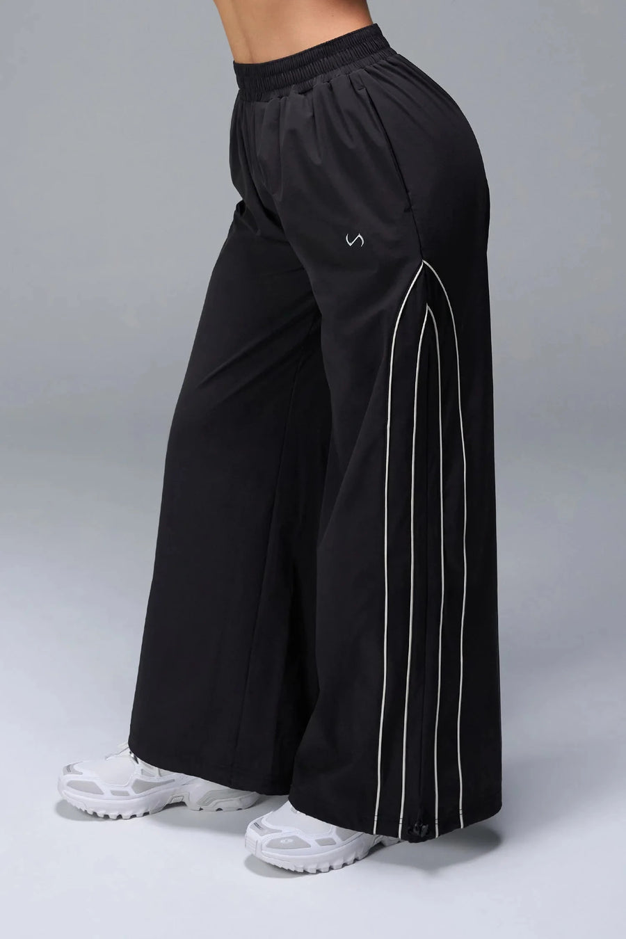 Side View of Black TLF Baggy Track Pants (Women’s GTS Gym-To-Street Edition) featuring side pockets and reflective piping details.