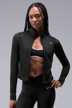 Front View of Black TLF Tempo Cropped Zip Up Jacket featuring thumbholes and cropped length for gym and lifestyle wear 