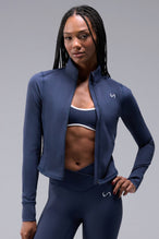 Front View of Blue TLF Tempo Cropped Zip Up Jacket featuring thumbholes and cropped length for gym and lifestyle wear 