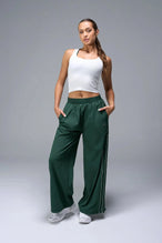 Front View of Green TLF Baggy Track Pants (Women’s GTS Gym-To-Street Edition) featuring side pockets and reflective piping details.
