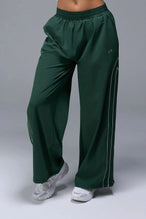 Front View of Green TLF Baggy Track Pants (Women’s GTS Gym-To-Street Edition) featuring side pockets and reflective piping details.
