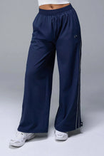 Front View of Blue TLF Baggy Track Pants (Women’s GTS Gym-To-Street Edition) featuring side pockets and reflective piping details.