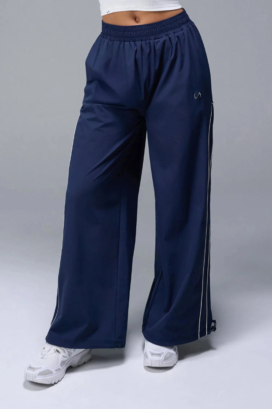 Front View of Blue TLF Baggy Track Pants (Women’s GTS Gym-To-Street Edition) featuring side pockets and reflective piping details.