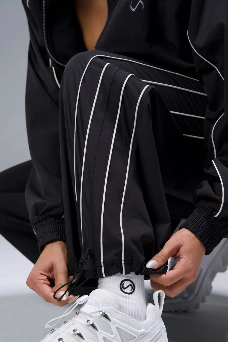 Detail View of Black TLF Baggy Track Pants (Women’s GTS Gym-To-Street Edition) featuring side pockets and reflective piping details.