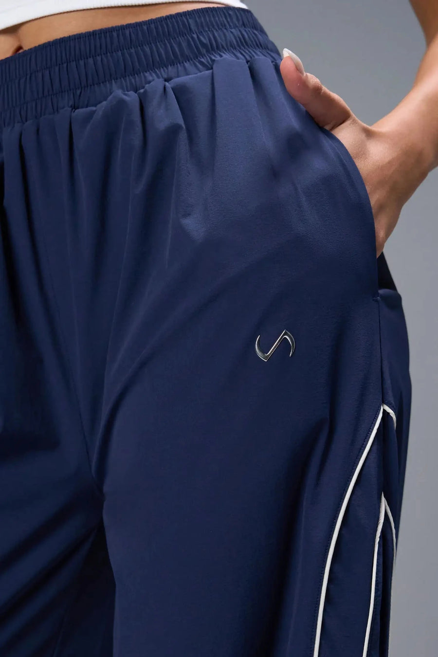 Front View of Blue TLF Baggy Track Pants (Women’s GTS Gym-To-Street Edition) featuring side pockets and reflective piping details.