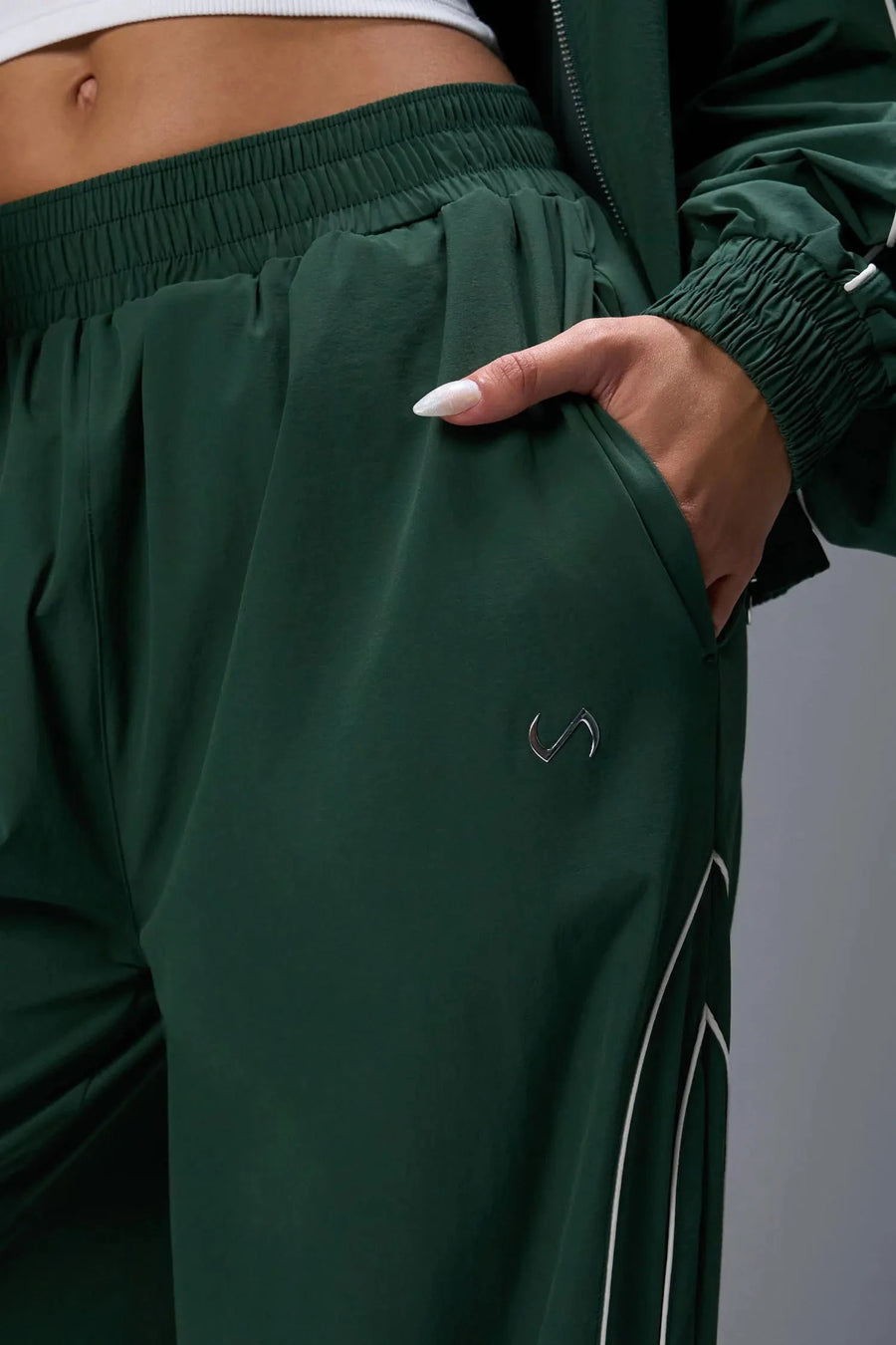 Front View of Green TLF Baggy Track Pants (Women’s GTS Gym-To-Street Edition) featuring side pockets and reflective piping details.